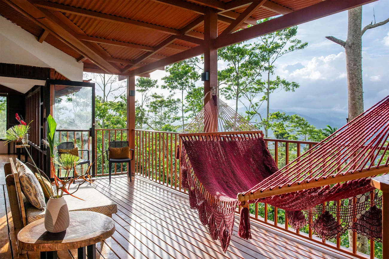 Terraza de Iriká con hamaca roja y vistas a las montañas de Turrialba, rodeada de naturaleza.
